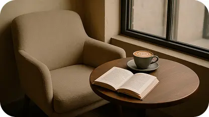 Cozy armchair beside a window with a small round table holding a coffee cup and an open book