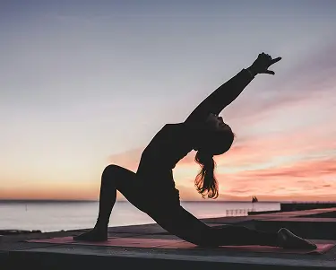 Woman practicing yoga at sunset